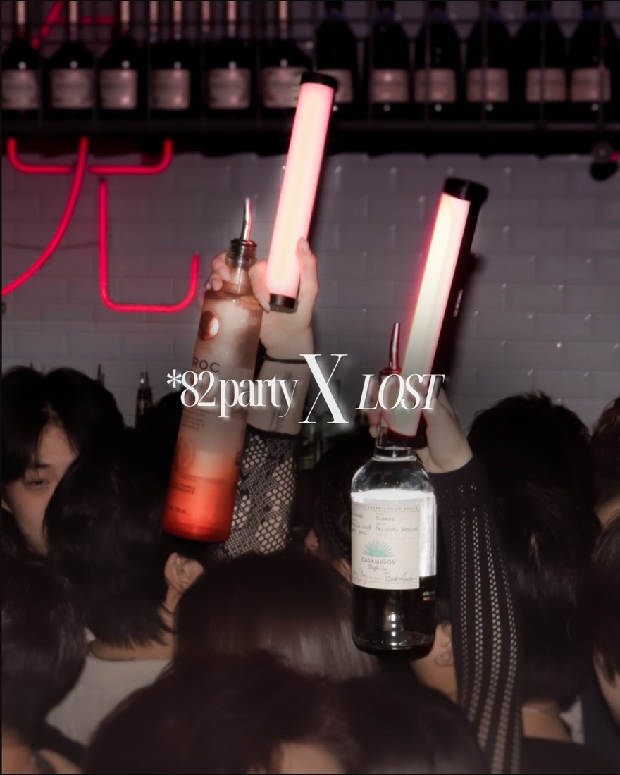 Bottles and glow sticks raised over the crowd at *82 party x LOST