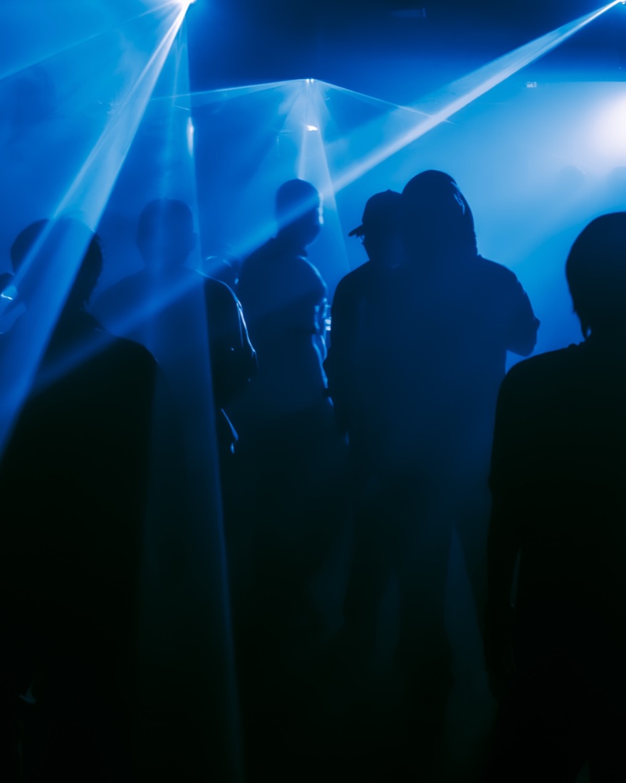 Blue laser beams over silhouetted dancers at De:code